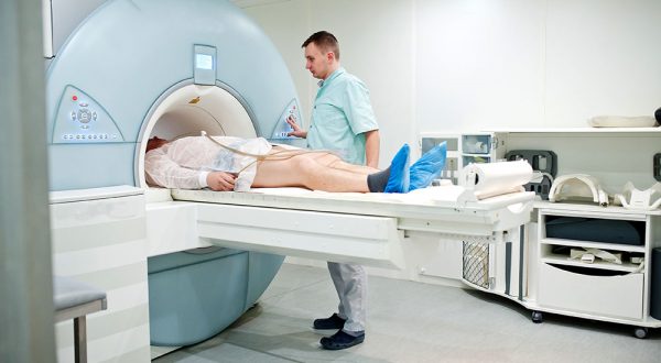 Male doctor turns on magnetic resonance imaging machine with patient inside.